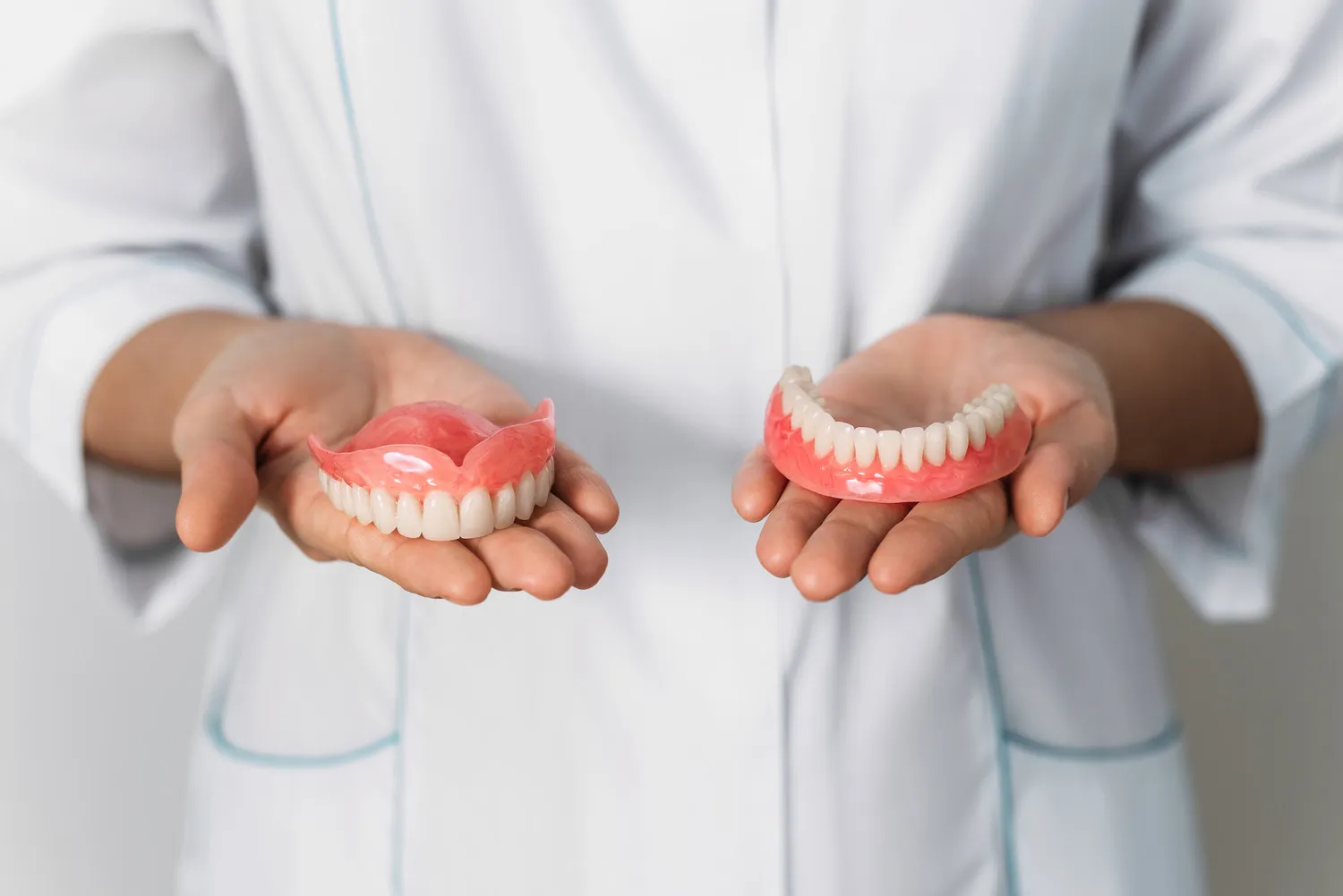 Skilled dental technician holding finished custom dentures, showing precision craftsmanship